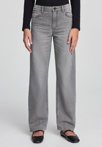 Jeans grigi ampi con cinque tasche, passanti per cintura e chiusura frontale con bottone. Tessuto in misto cotone con una morbida texture e dettagli di cucitura minimi.