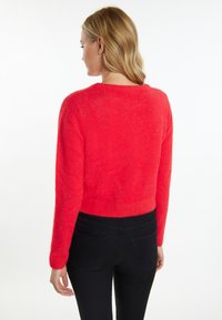 Rode, fuzzy cropped trui met lange mouwen en een ronde halslijn, gecombineerd met zwarte slim-fit jeans, met detailweergave van de achterkant.