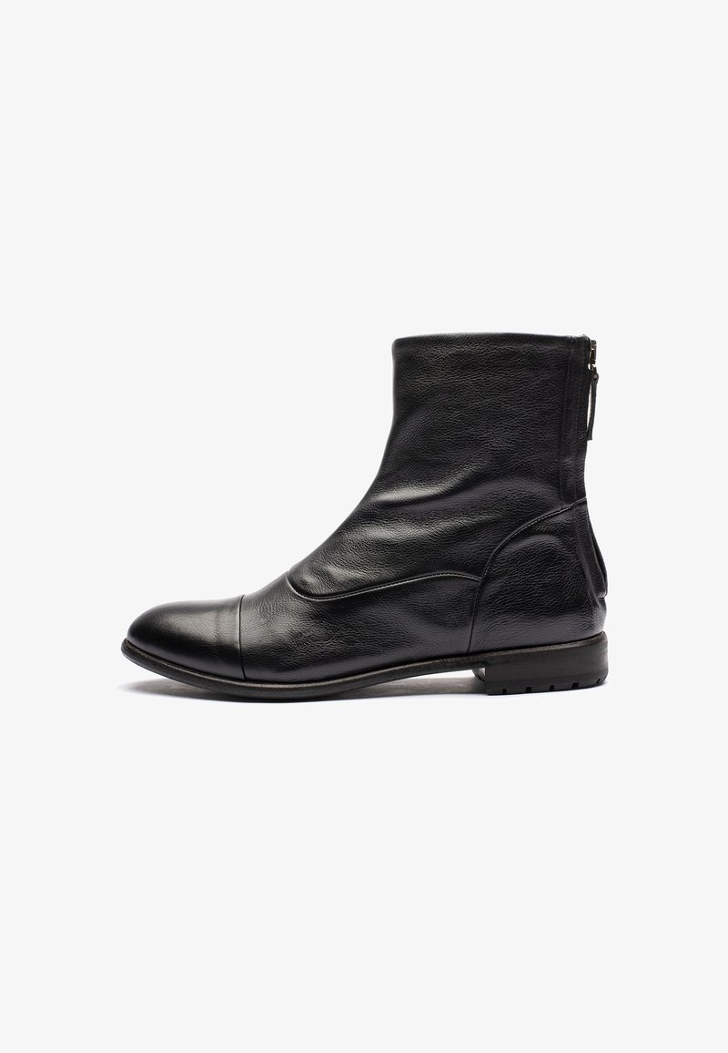 Stivaletto in pelle nera con una texture liscia, punta arrotondata, dettagli di cucitura delicati e chiusura con zip sul retro. Suola piatta.