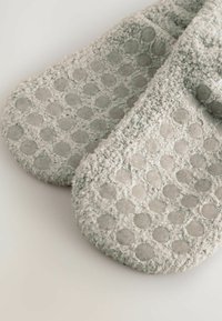 Pantofole grigie con trama che presentano un motivo a pois sollevati sulle suole. Realizzate in materiale morbido con una finitura soffice, garantiscono una vestibilità perfetta.