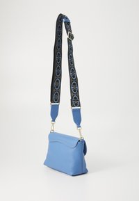 Borsa a mano blu in pelle con finitura texturizzata, dotata di un top curvo, hardware dorato e una tracolla staccabile con motivo in bianco e blu.