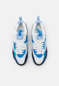 Sneakers Nike con una toma in mesh bianco, dettagli blu, suola in gomma nera e lacci prominenti. Le caratteristiche includono una linguetta imbottita e un dettaglio con il logo.