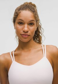 Gaiši rozā sporta krūšturis ar plāniem regulējamiem siksniņām un ribota tekstūra. Tam ir minimālisma dizains un kvadrātveida kakla izgriezums.