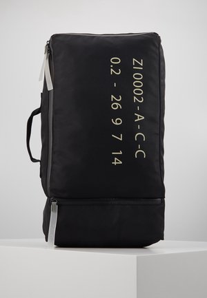 Black rectangular travel bag with side handle, two zippers, and beige text reading "ZI0002-A-C-C 0.2 - 26 9 7 14" on front panel.
