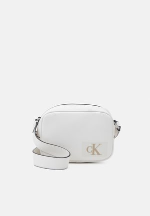 Bolso bandolera blanco con textura lisa, cierre de cremallera y logo dorado "cK" en el lateral. Correa ajustable con costuras en contraste.