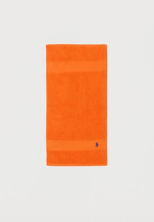 Toalla naranja brillante con bandas texturizadas y pequeño logo azul bordado en la esquina inferior derecha sobre un fondo blanco liso.