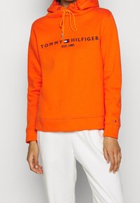 Oranje capuchontrui met koord, voorzien van een logo in marineblauw, geribbelde manchetten en een rechte zoom. Zacht, katoenmenging materiaal.