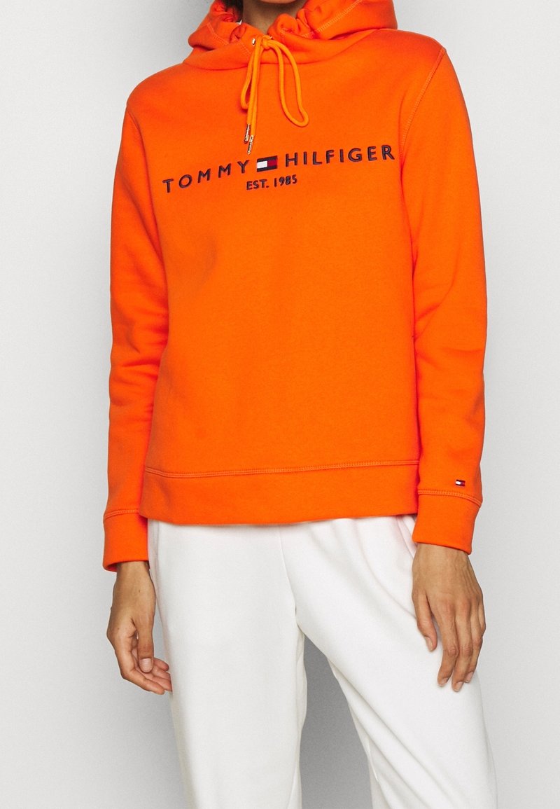 Oranje capuchontrui met koord, voorzien van een logo in marineblauw, geribbelde manchetten en een rechte zoom. Zacht, katoenmenging materiaal.