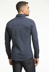 Mörkblå långärmad kn�äppt skjorta med en texturerad tyg och en klassisk krage. Har knäppte manschetter och en rundad fåll.