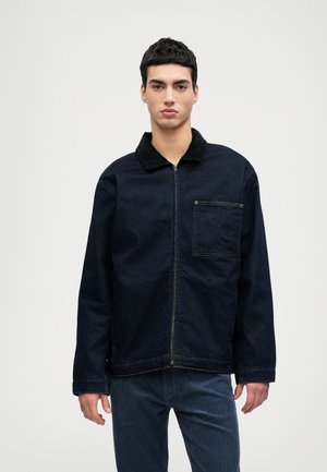 Dunkelblaue Jeans-Jacke mit Reißverschluss, einem schwarzen Kragen, einer Tasche vorne und lockerer Passform. Der Stoff hat eine glatte Textur mit sichtbaren Nähdetails.