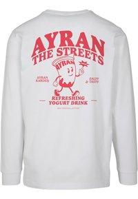 Fehér hosszú ujjú póló, piros grafikai nyomattal, amely egy joghurtital karakterét ábrázolja, alatta a "AYRAN THE STREETS" felirattal és további részletekkel.