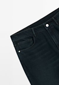 Jeans en denim noir avec poche avant visible, passants de ceinture, et fermeture par bouton argenté sur fond blanc.