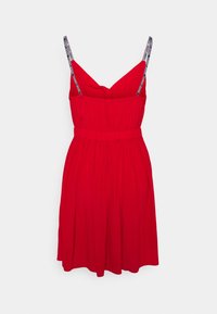 Vestido rojo con un corsé ajustado, falda acampanada y tirantes finos que presentan una marca. Está hecho de una tela ligera y tiene una textura fruncida.