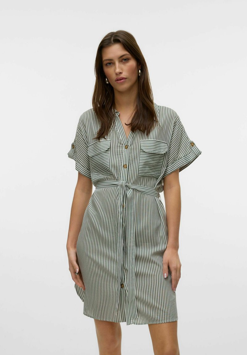 Vestido a rayas en verde y blanco, con mangas cortas, dos bolsillos frontales, cierre de botones, cintura ceñida con cinta a juego. Textura de tela suave.