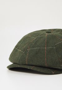 Green houndstooth cap featuring a structured design, flat brim, contrasting red and white check pattern, and a central top button.
