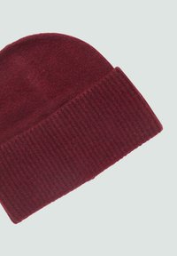 Burgundy knit beanie with a textured ribbed cuff, soft wool-like material, and a rounded top design.