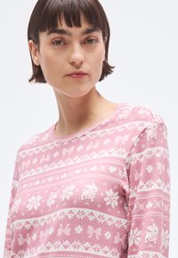 Różowy sweter z długimi rękawami z białymi, dzierganymi wzorami, w tym kokardkami i zwierzętami; okrągły dekolt z guzikiem na ramieniu.