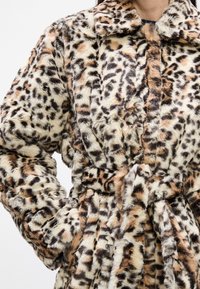 Kryté kožušinové sako s leopardím vzorom v odtieňoch hnedej, krémovej a čiernej, s opaskom v páse a klobúkovým golierom. Jemná textúra.