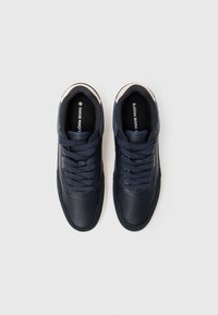 Baskets bleu marine avec une tige en cuir, un embout texturé, un design à lacets et des accents crème contrastants sur le col et le côté.