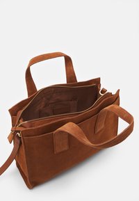 Sac à main en suede marron avec fermeture éclair, double poignées et une poche intérieure. Surface texturée et un design spacieux et organisé.