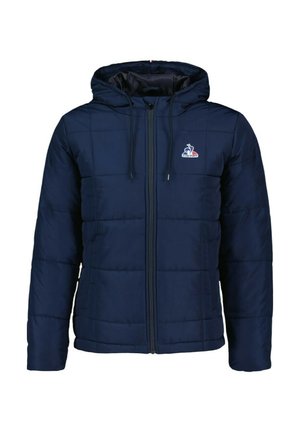 Chaqueta acolchada de color marino con capucha, que presenta un cierre de cremallera en la parte delantera, puños elásticos y un logo en el pecho. La tela parece suave con un patrón acolchado.