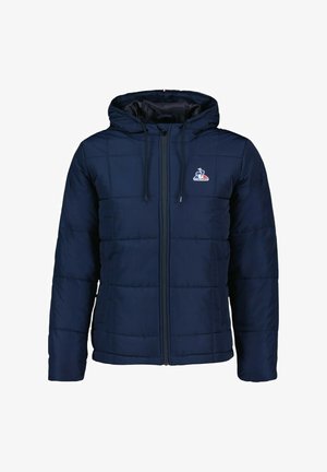 Chaqueta acolchada de color marino con capucha, que presenta un cierre de cremallera en la parte delantera, puños elásticos y un logo en el pecho. La tela parece suave con un patrón acolchado.