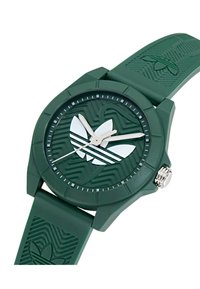Montre en silicone verte avec bracelet texturé, cadran rond, accents de logo blancs et marqueurs d'heure minimalistes. Dispose de mains argentées et d'une conception résistante à l'eau.