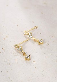 Pendientes de oro colgantes que presentan múltiples piedras preciosas transparentes de diferentes tamaños, sujetos a un delgado vástago, con un acabado elegante y pulido.