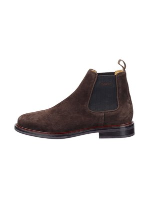 Braune Wildleder-Chelsea-Boots mit elastischen Seitenpaneelen, einer Schlaufe und einer schwarzen Gummisohle, die rund um die Basis einen dezenten roten Akzent aufweist.