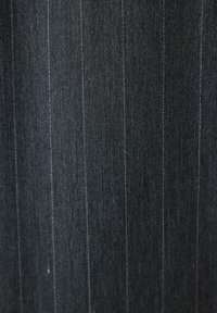 Donkergrijze stof met subtiele verticale streepjes, die een fijne geweven textuur en lichte variaties in schaduw toont.