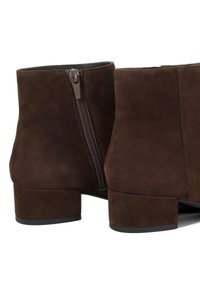 Bruine suède enkelboots met een ritssluiting aan de zijkant, vierkante blokhak en een gladde textuur, die een minimalistisch ontwerp laten zien.