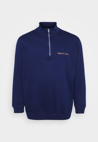 Sudadera de media cremallera azul marino hecha de un tejido suave. Presenta un collar alto, puños acanalados y el texto "Originals Studio" bordado en un color en contraste.