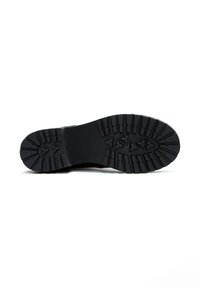Suela de bota de goma negra con patrón de textura, que presenta estrías y ranuras de agarre para tracción y durabilidad.
