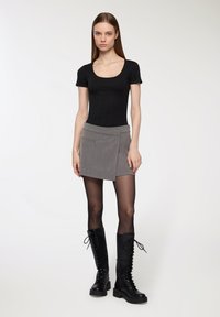 Czarna bluzka z krótkim rękawem i okrągłym dekoltem, zestawiona z szaro-skalną mini spódnicą z bocznymi kieszeniami oraz czarnymi, do kolan, sznurowanymi botkami.