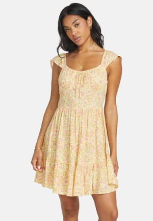 Robe florale jaune avec des manches courtes à volants, décolleté carrée, détail à cordon à l'avant et jupe évasée avec un ourlet ondulé.