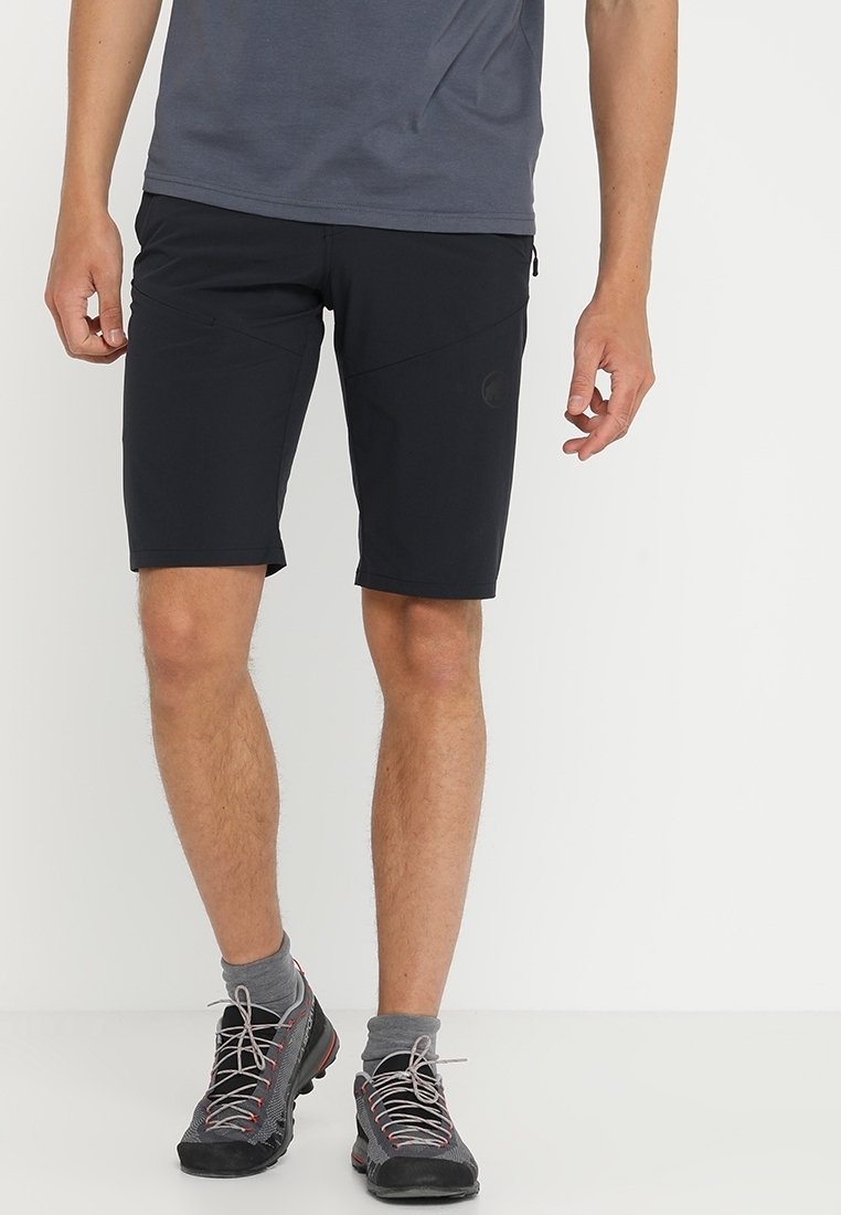 Svarta herrshorts i stretchmaterial med sidofickor, en figurnära design och en mjuk textur. Tillsammans med grå sportskor.