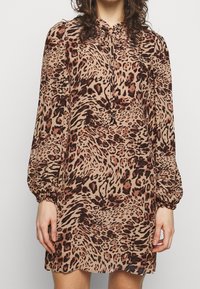 Leopardenmuster Mini-Kleid mit langen Puffärmeln, gerafften Manschetten und einer Bindebrust. Hergestellt aus einem glatten, leichten Stoff in erdigen Tönen.