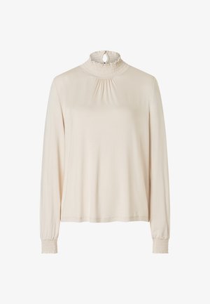 Long-sleeve beige top with a high, smocked neck and keyhole detail. Features gathered texture at the neck and smocked cuffs. Soft, lightweight fabric.