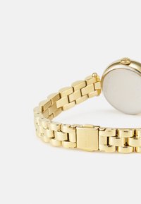 Gold-tone stainless steel watch with a round case, polished finish, link bracelet, and a clasp closure. Back displays brand name.