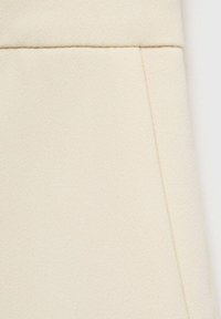 Béžová strukturální tkanina se jemným povrchem, s rovnými švy. Ideální pro oděvy vyžadující lehký a prodyšný materiál.
