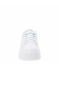 Sneaker bianco con parte superiore in pelle liscia, punta arrotondata, dettagli perforati sulla scatola delle dita e una suola spessa e imbottita di colore bianco.