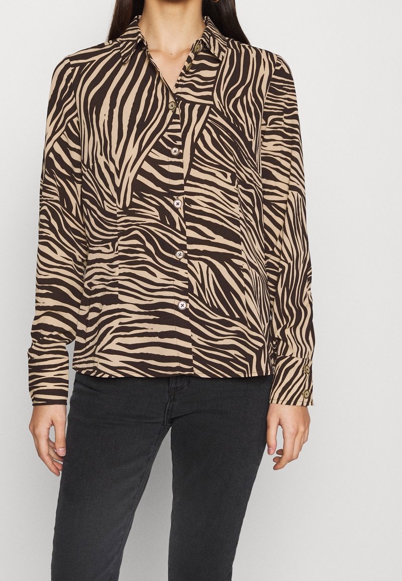 Beige- und braun gestreiftes Hemd mit Zebra-Muster, langen Ärmeln und Kragen, das eine leicht lockere Passform und geknöpfte Manschetten hat.