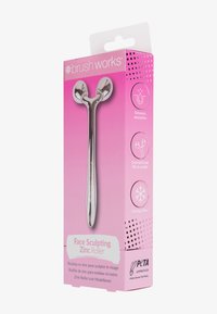 Sølv sink ansiktsruller med dobbelt kulehoder i et elegant design, vist i en rosa pakke med produktdetaljer og PETA-godkjenning.