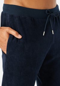 Marineblå kordfløjl loungebukser med ribbet tekstur, elastisk talje, justerbar snøring og sidelommer.