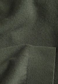 Tissu tricoté vert foncé avec détail de bord-côtes, texture douce et légères plis.