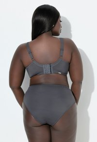 Szary biustonosz z regulowanymi ramiączkami i zapięciem na haftki, w zestawie z szarymi majtkami z wysokim stanem. Gładka tkanina z minimalnymi zdobieniami.