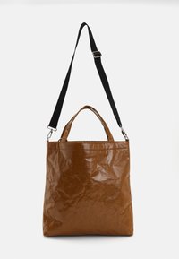 Sac fourre-tout en papier brun avec une finition texturée, doté de courtes poignées et d'une bandoulière noire amovible.