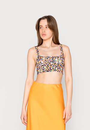 Top crop floral com fundo preto, apresentando flores coloridas. Decote quadrado e alças largas. Combinado com uma saia laranja sólida.