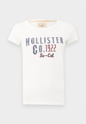 T-shirt bianco in cotone con scollo rotondo e maniche corte. Sul davanti presenta un testo stampato blu e rosso: "HOLLISTER CO. 1922 So-Cal."