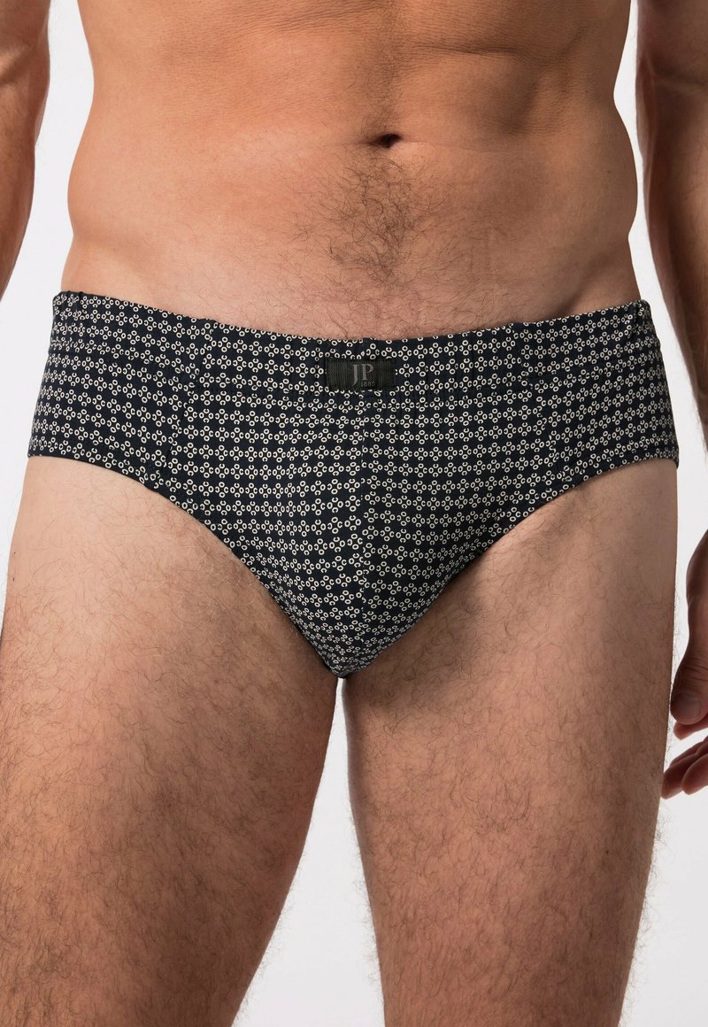Slip da bagno da uomo, base nera con un motivo geometrico bianco, vita uniforme, forma aderente, realizzato in tessuto elasticizzato, texture liscia.